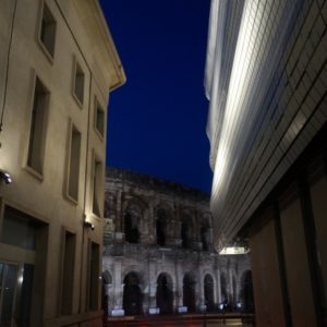 vue en perspective depuis une rue jouxtant le musée - les arènes de Nîmes en arrière plan