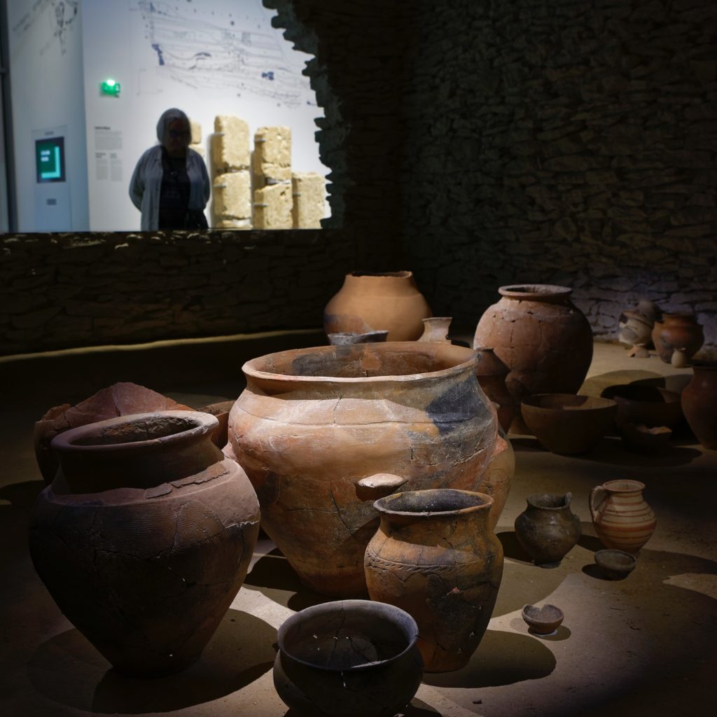 femme observant la reconstitution de l'intérieur de la maison de Gailhan et ses céramiques