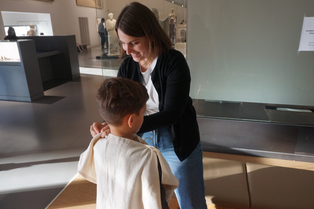 Une médiatrice du musée habille un enfant au milieu des collections